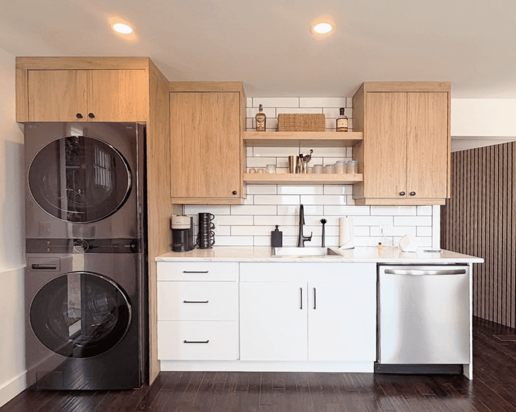 A modern micro kitchen suite by Westwood Cabinetry in Kelowna, featuring integrated laundry, white high-gloss cabinets, and oak-finish upper cabinetry with a white subway tile backsplash.