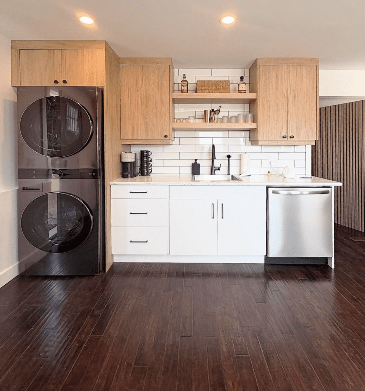 A modern micro kitchen suite by Westwood Cabinetry in Kelowna, featuring integrated laundry, white high-gloss cabinets, and oak-finish upper cabinetry.
