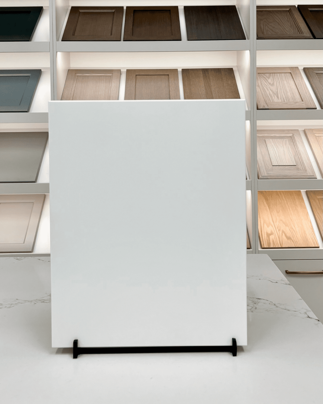 A sleek, white Modern Slab cabinet door style with a completely flat, seamless surface for a minimalist kitchen design, displayed in a showroom.