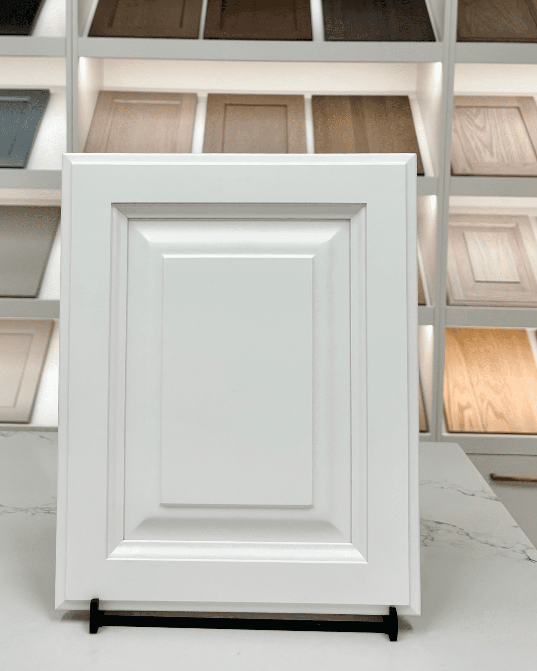 A traditional white Raised Panel cabinet door featuring a detailed, elevated center panel and contoured edges, showcased on a marble countertop.