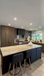 Custom kitchen cabinetry featuring warm wood tones, a large island with stone countertops, black bar stools, and a black range hood.